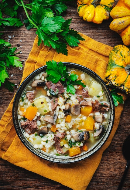 Foto comida caseira de inverno sopa quente com abóbora cogumelos legumes carne e cevada mesa de madeira rústica vista superior