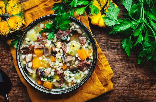 Comida caseira de inverno Sopa quente com abóbora cogumelos legumes carne e cevada Mesa de madeira rústica vista superior