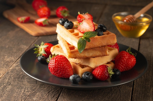 Comida caseira fresca de waffles belgas de baga com mirtilo de morango e chocolate de mel