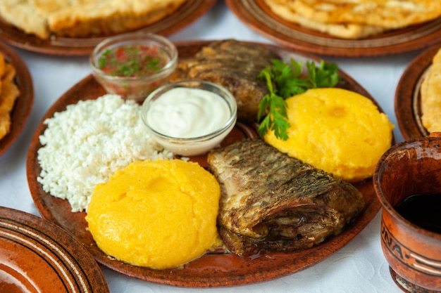 Comida caseira romena com peixe grelhado, tortas de polenta vegetais com vinho tinto