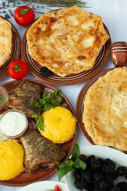 Comida caseira romena com peixe grelhado, tortas de polenta vegetais com vinho tinto