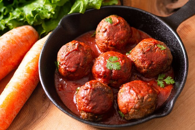 Comida caseiro almôndega picante orgânica em ferro fundido em fundo de madeira