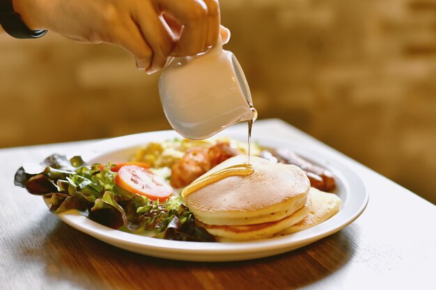 Comida casera para el desayuno, pila de panqueques con sirope, ensalada y huevos revueltos.