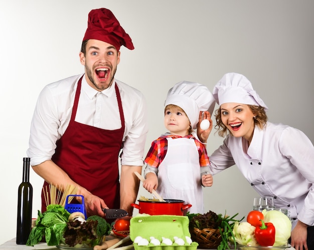 Comida casera familia feliz en la cocina comida sana en casa niño adorable en preparación de gorro de cocinero para