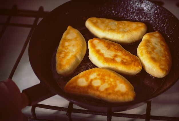 Comida casera. La mano que sostiene la sartén donde frías pasteles deliciosos.