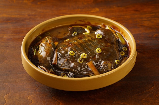 Comida china especial Tortuga de caparazón blando estofada con cebolletas sobre un fondo vintage oscuro