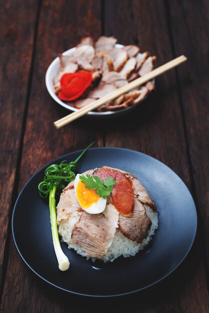 Comida chinesa, arroz com carne de porco frita e agg na madeira