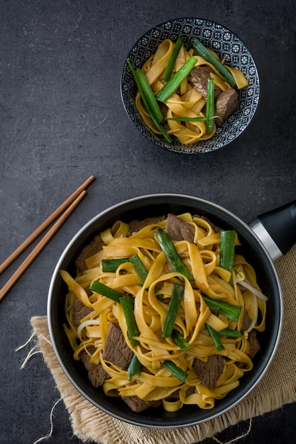 Comida chinesa carne mein na frigideira em preto