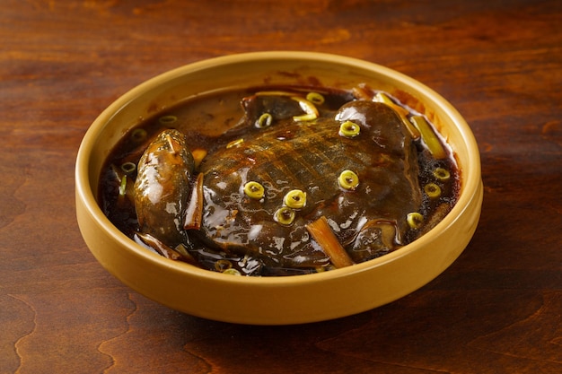 Comida chinesa especial Tartaruga de casca mole refogada com cebolinha em um fundo vintage escuro