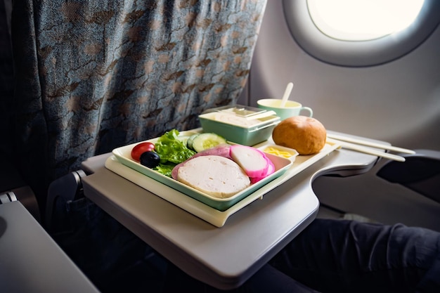 Comida Clase Turista Aerolíneas para comida en el avión para alimentar a los pasajeros conjunto de alimentos primer plano vista superior salchicha con ensalada y pan y postre en un plato en la mesa plegable en avión