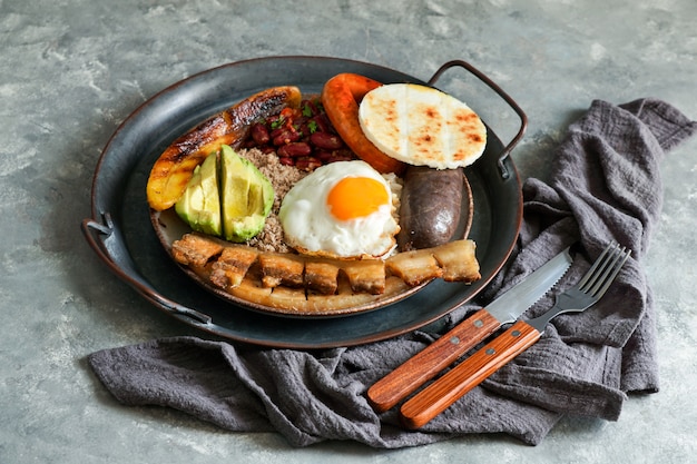 Comida colombiana. Bandeja paisa, prato típico na região Antioquia da Colômbia - chicharron (barriga de porco frito), morcela, salsicha, arepa, feijão, banana frita