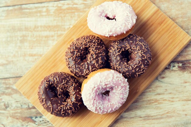 comida, comida chatarra y concepto de alimentación - primer plano de donuts glaseados en tablero de madera