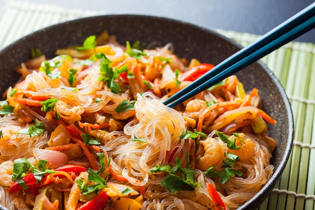 Comida coreana salteada no prato quente da panela com pauzinhos