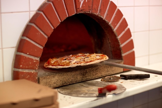comida, cozinha italiana e conceito de culinária - descasque tirando pizza assada do forno na pizzaria