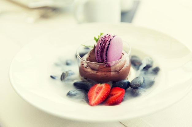 comida, culinaria, alta cocina y concepto de cocina - cierre de postre de chocolate con galleta macaron y fresa fresca en el restaurante