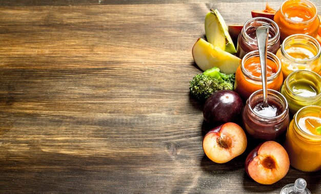 Comida de bêbe. Variedade de purês para bebês de frutas e vegetais. Em uma mesa de madeira.