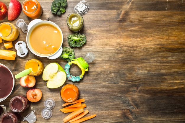 Comida de bêbe. Vários purês de frutas e vegetais. Sobre um fundo de madeira.