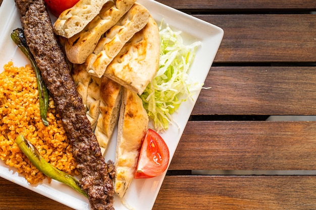 Comida de carne tradicional turca Adana kebab ou kebap com pimentões marinados, pão e arroz pilaf Vista superior Copiar espaço