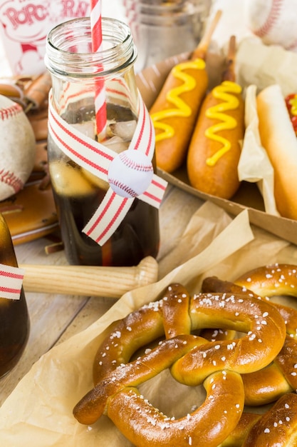 Comida de festa de beisebol com bolas e luva em uma mesa de madeira.