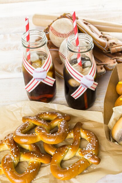 Comida de festa de beisebol com bolas e luva em uma mesa de madeira.