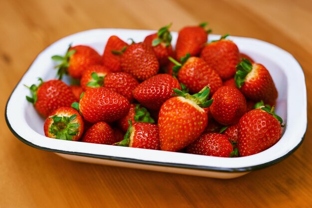 Foto comida de frutas e tigela de morango na cozinha de casa em bancada de madeira para dieta ou nutrição saúde, bem-estar e perda de peso com bagas na superfície no apartamento para minerais ou vitaminas de desintoxicação