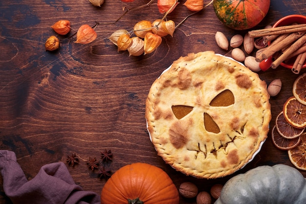 Comida de Halloween. Torta de abóbora caseira ou torta com uma cara assustadora para o Halloween em uma mesa de madeira. Copie o espaço. Conceito de comida de Halloween.