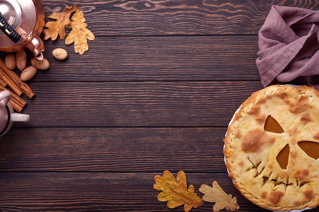 Comida de Halloween. Torta de abóbora caseira ou torta com uma cara assustadora para o Halloween em uma mesa de madeira. Copie o espaço. Conceito de comida de Halloween.