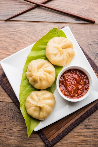 Comida de momos de bolinho tradicional do Nepal servido com chutney de tomate sobre um fundo temperamental. Foco seletivo