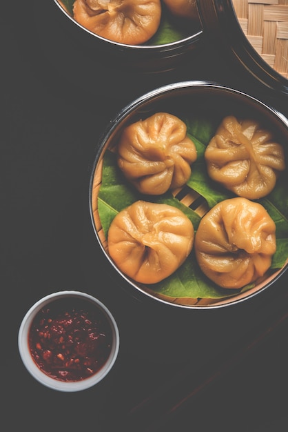 Comida de momos de bolinho tradicional do Nepal servido com chutney de tomate sobre um fundo temperamental. Foco seletivo