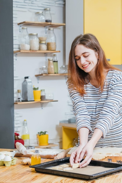 Comida de padaria e pastelaria Senhora alegre organizando massa na assadeira fazendo biscoitos de gengibre