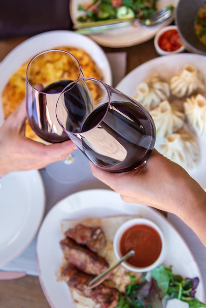 Comida de restaurante georgiano na mesa com vinho nas mãos