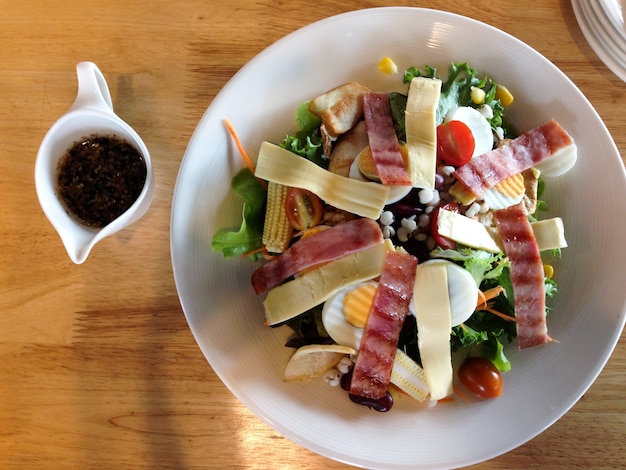 Foto comida de restaurante, salada caesar, isolada na mesa de madeira, vista superior