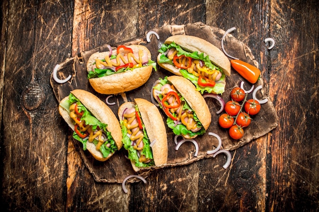 Comida de rua. cachorro-quente com ervas, legumes e mostarda quente na mesa de madeira.