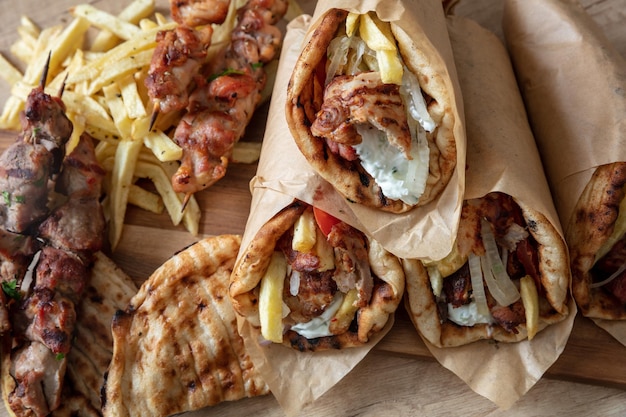 Foto comida de rua grega giroscópio fatias de carne pita pão envolver e souvlaki espeto acima da cabeça