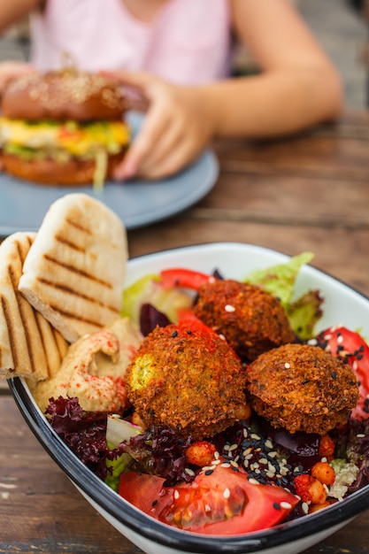 Comida de rua israelense. Salada do Falafel com hummus, beterraba e vegetais na bacia em um restaurante.