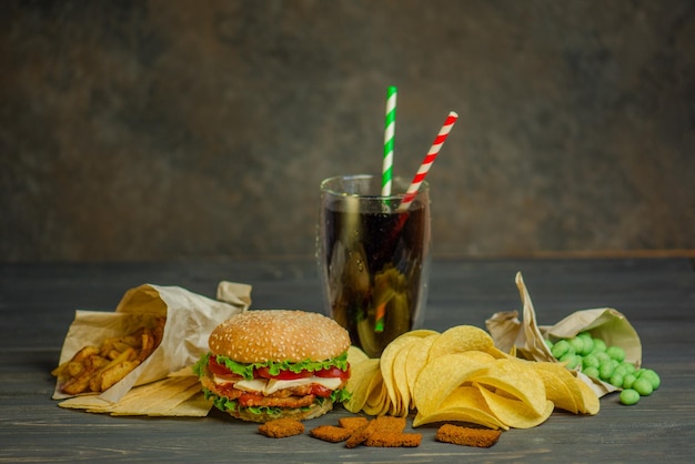 Comida de rua ou fast food. Hambúrguer, batata frita e coca-cola na mesa com fundo de madeira. Hambúrguer insalubre com carne.