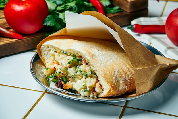Comida de rua vegan saborosa - Pita com couve-flor, cebola e molho, numa mesa branca. Cozinha grega. Visão.