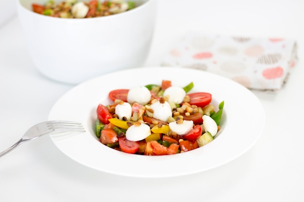 Comida deliciosa: ensalada saludable de verano casera con tomates en un plato blanco, primer plano