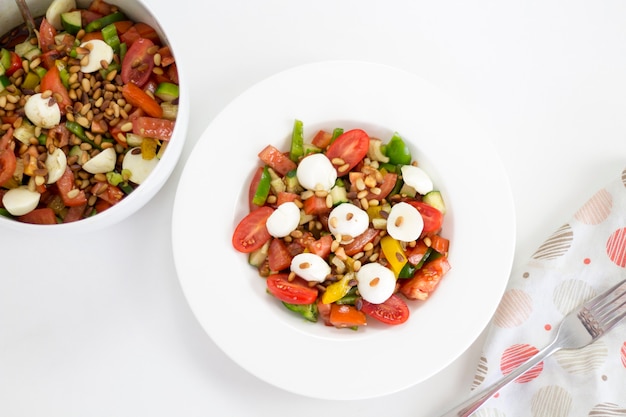 Comida deliciosa: ensalada saludable de verano casera con tomates en un plato blanco, primer plano