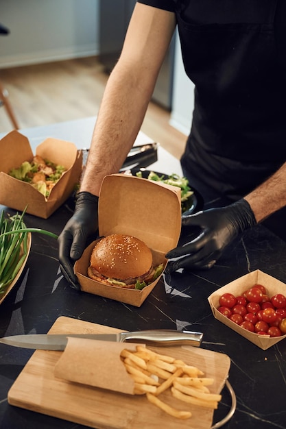 Comida deliciosa El hombre está empaquetando comida en las cajas de papel ecológico Restaurante interior