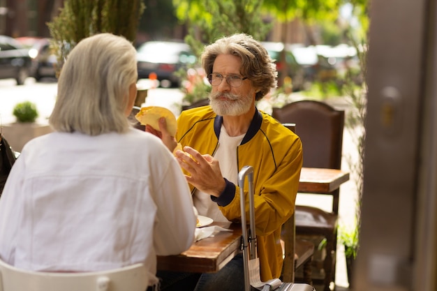 Comida deliciosa. Homem feliz almoçando com sua esposa em um restaurante mexicano sentado à mesa na rua.