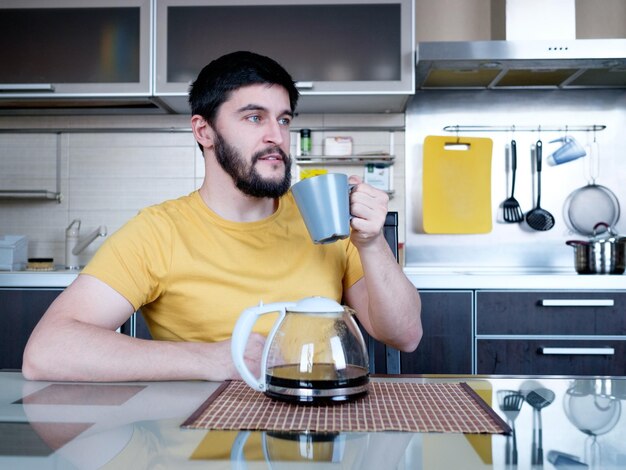 Foto comida divertida hombre caucásico atractivo bebiendo café en la cocina