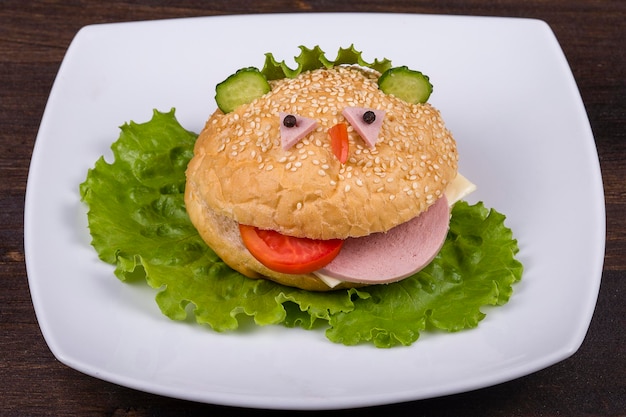 Comida divertida para niños hamburguesa parece un hocico gracioso en un plato blanco de cerca