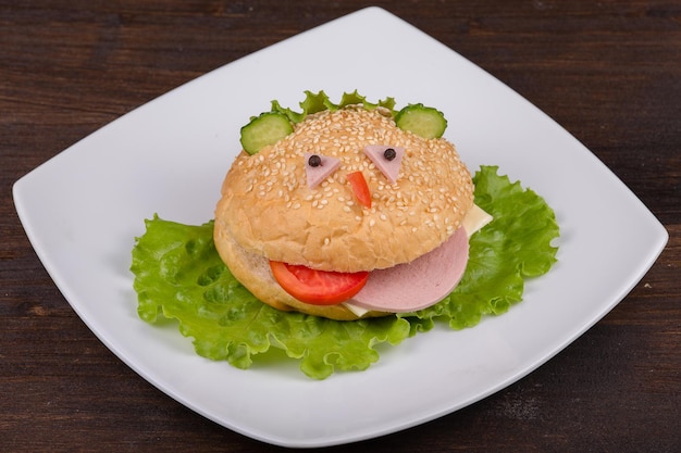 Comida divertida para niños, la hamburguesa parece un hocico gracioso en un plato blanco de cerca
