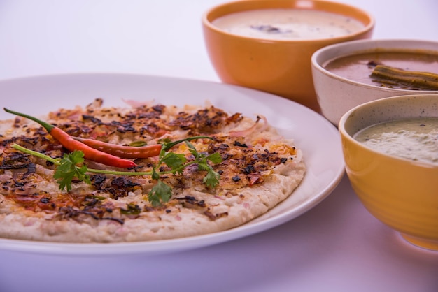 Comida do sul da índia uttapam ou ooththappam ou uthappa é um prato semelhante aos dosa feito com ingredientes cozidos em uma massa, servido com chutney de coco, chutney verde e sambar