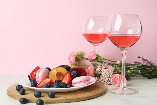 Comida doce, vinho e flores contra um fundo rosa