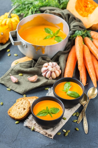 Comida e bebida ainda vida dieta e conceito de nutrição Outono sazonal sopa de cenoura abóbora laranja assada com ingredientes em uma mesa de madeira rústica Fundo de cozinha aconchegante