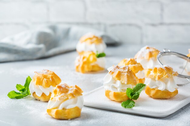 Comida e bebida, conceito de férias. Deliciosos profiteroles doces caseiros com creme em uma mesa de cozinha moderna