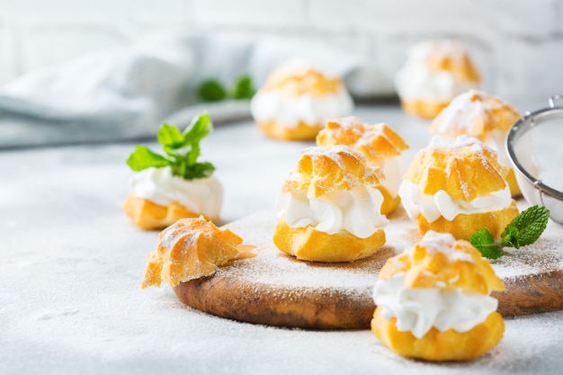 Comida e bebida, conceito de férias. Deliciosos profiteroles doces caseiros com creme em uma mesa de cozinha moderna