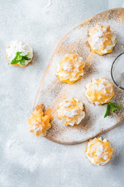 Comida e bebida, conceito de férias. Deliciosos profiteroles doces caseiros com creme em uma mesa de cozinha moderna